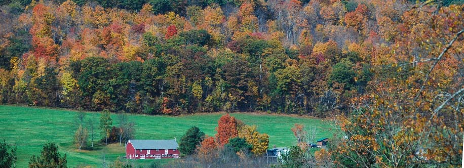 Red farmhouse in New England surronded by fall color